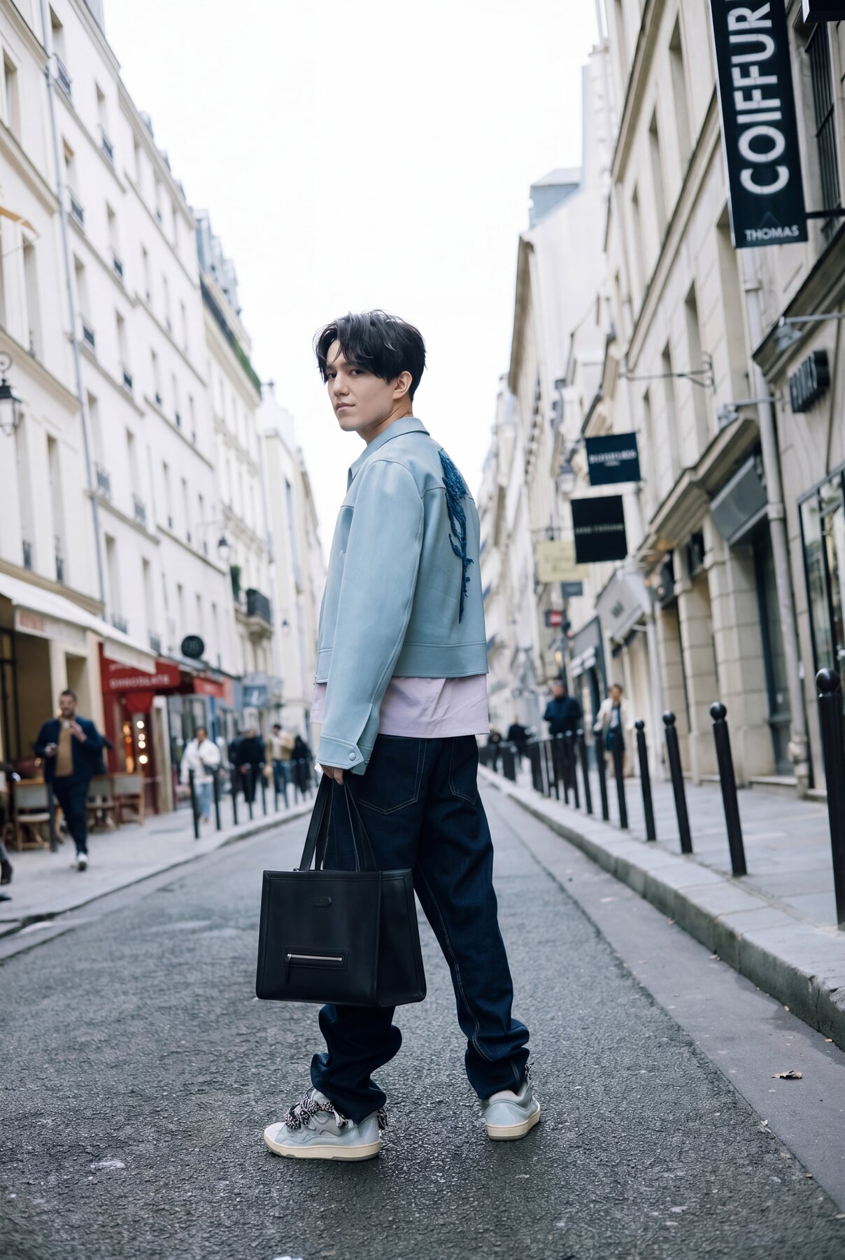 Dimash on a Paris street, blue jacket, tote bag