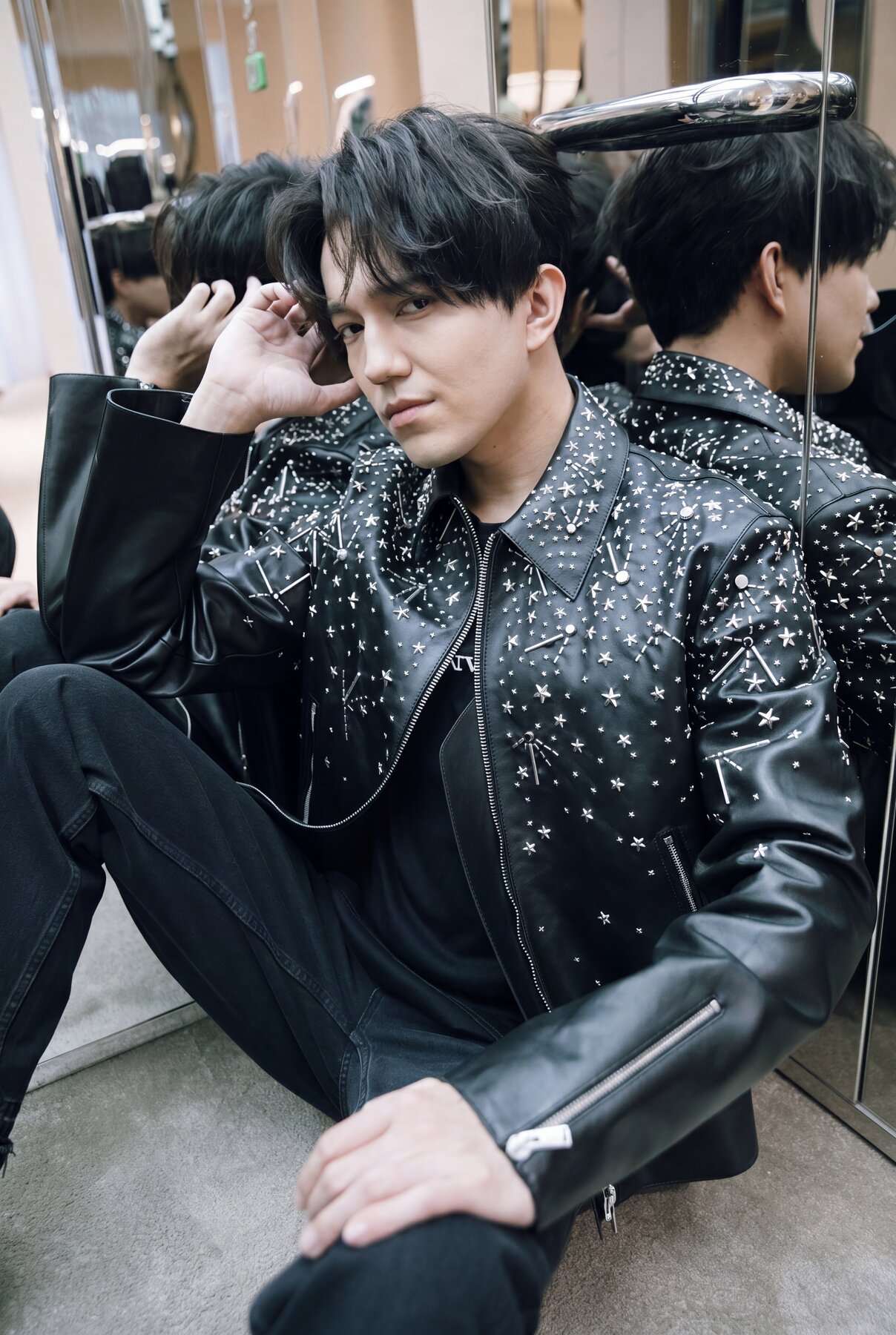 Dimash in studded jacket, seated, mirror reflections