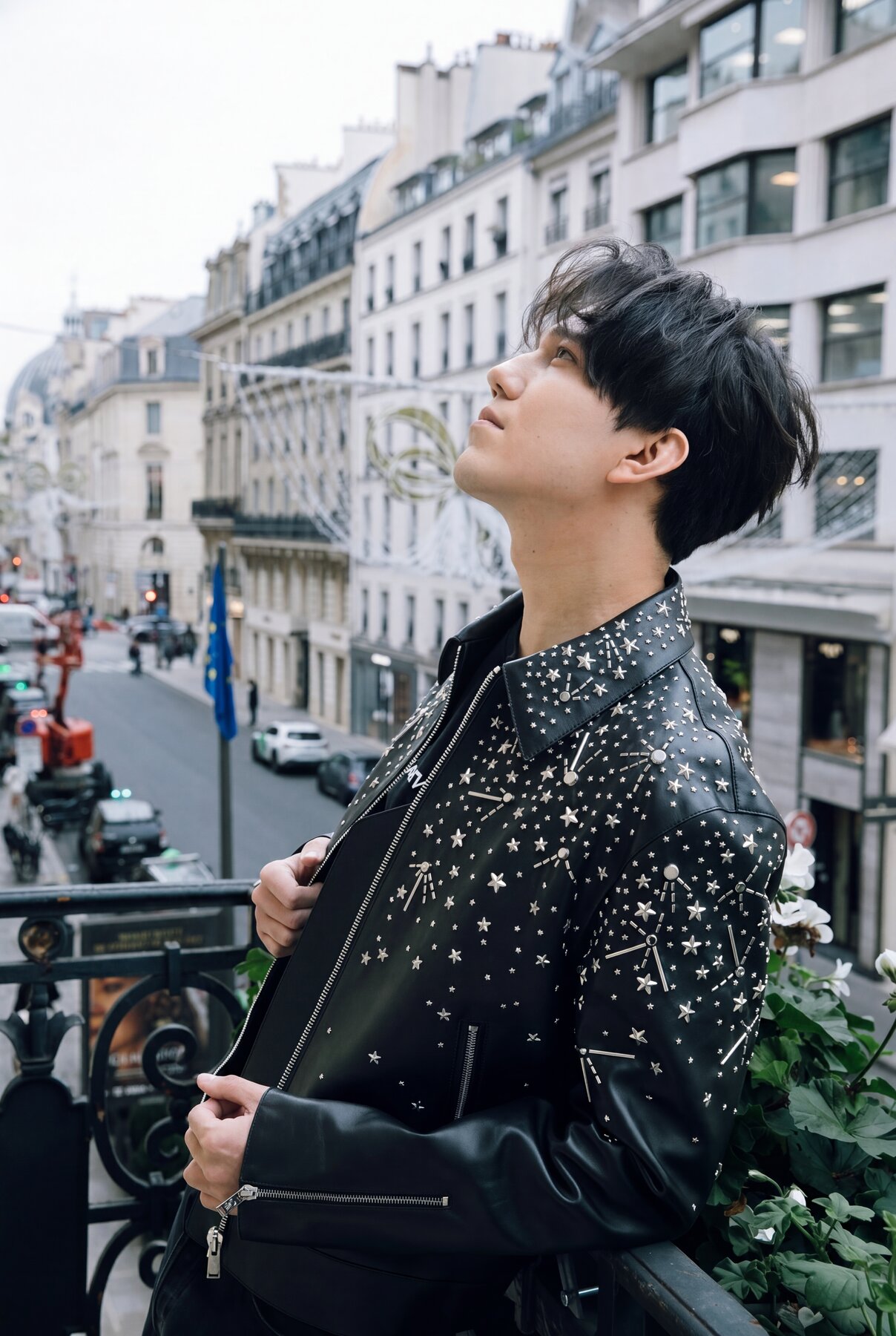 Dimash on a Paris balcony, looking up, studded jacket