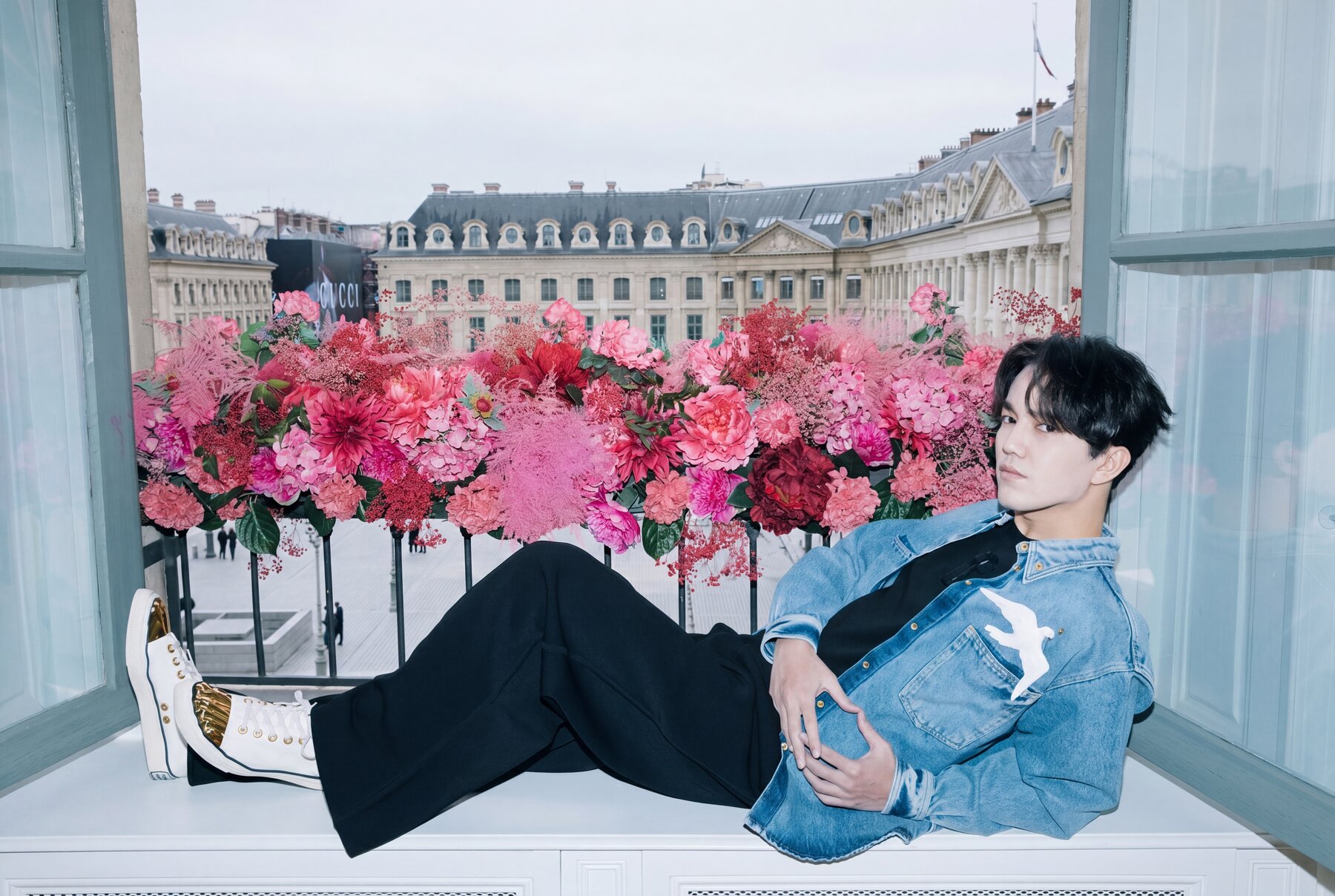 Dimash reclining at Place Vendôme, denim and flowers