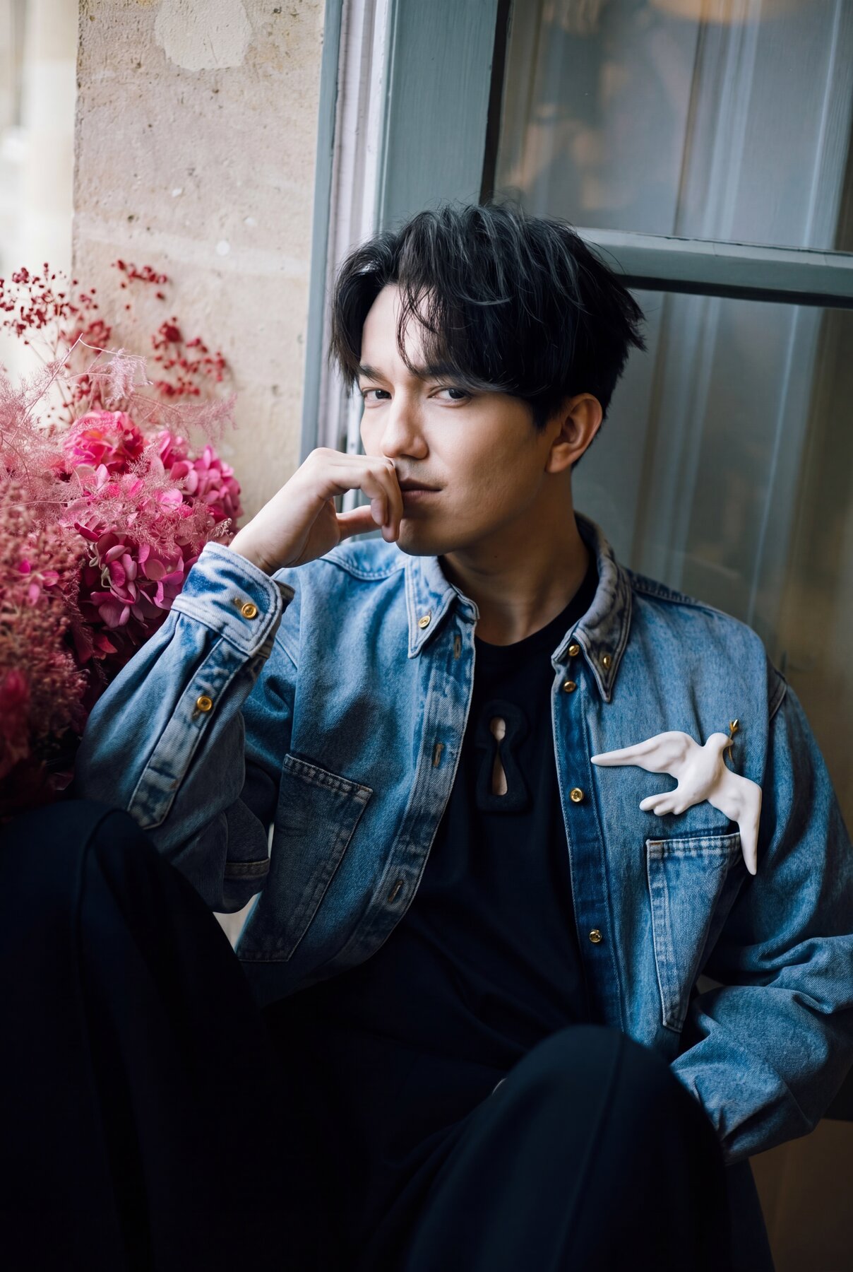Dimash in denim, contemplative, pink flowers in background